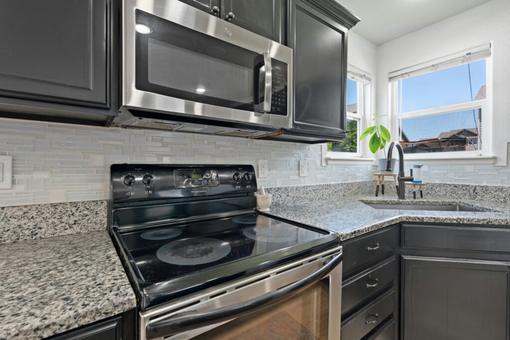 Stylish modern kitchen with stainless steel microwave, stove, and granite countertops.